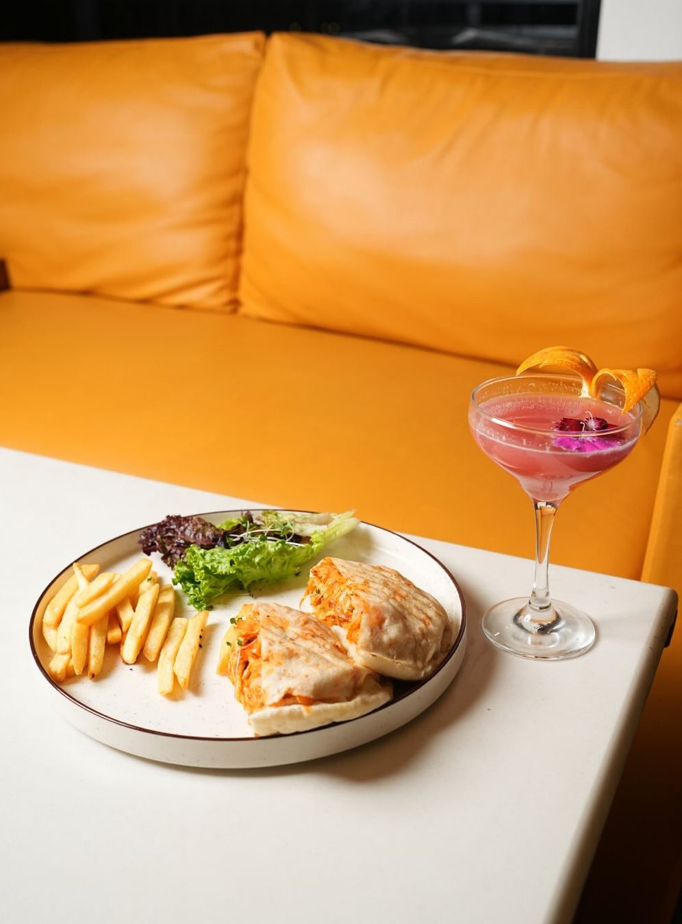 Wrap with fries and a pink cocktail glass on a white table