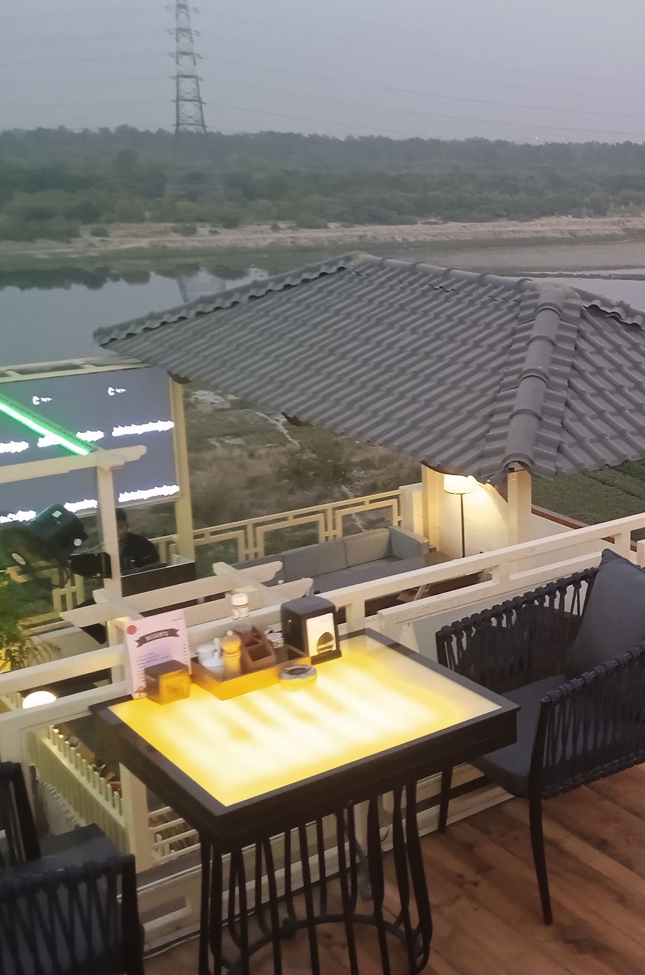 Rooftop tables lit from within, overlooking the river at dusk